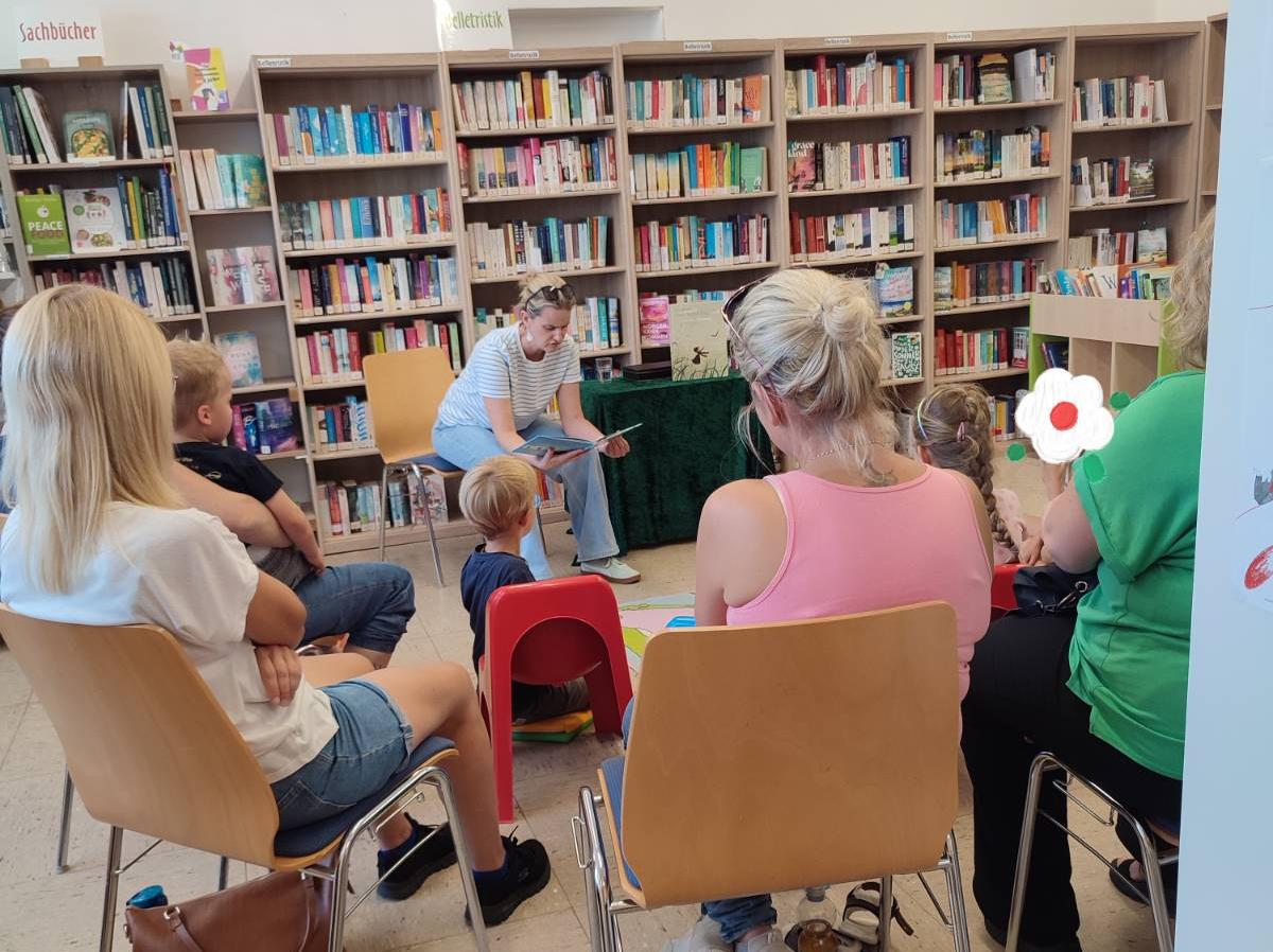 Kinder und Erwachsene hören einer Lesung zu