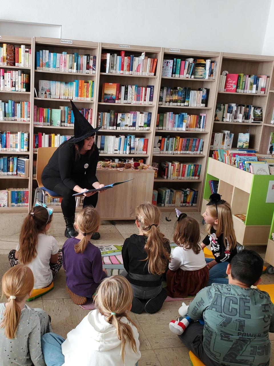Frau liest Buch vor Kindern vor